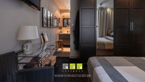 Ein modernes Hotelzimmer mit einem großen Bett, einem Schreibtisch mit Lampe, einem Kleiderschrank und einem durchgegangenen Badezimmer.