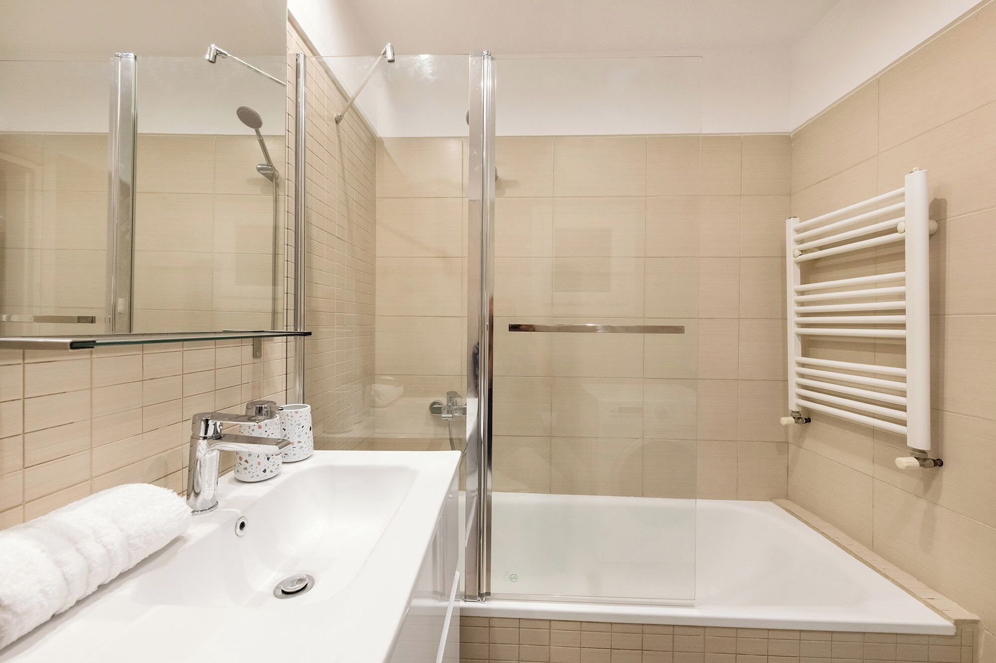 Ein modernes Badezimmer mit einer gläsernen Duschkabine, einer Badewanne und einem weißen Waschbecken mit Spiegel.