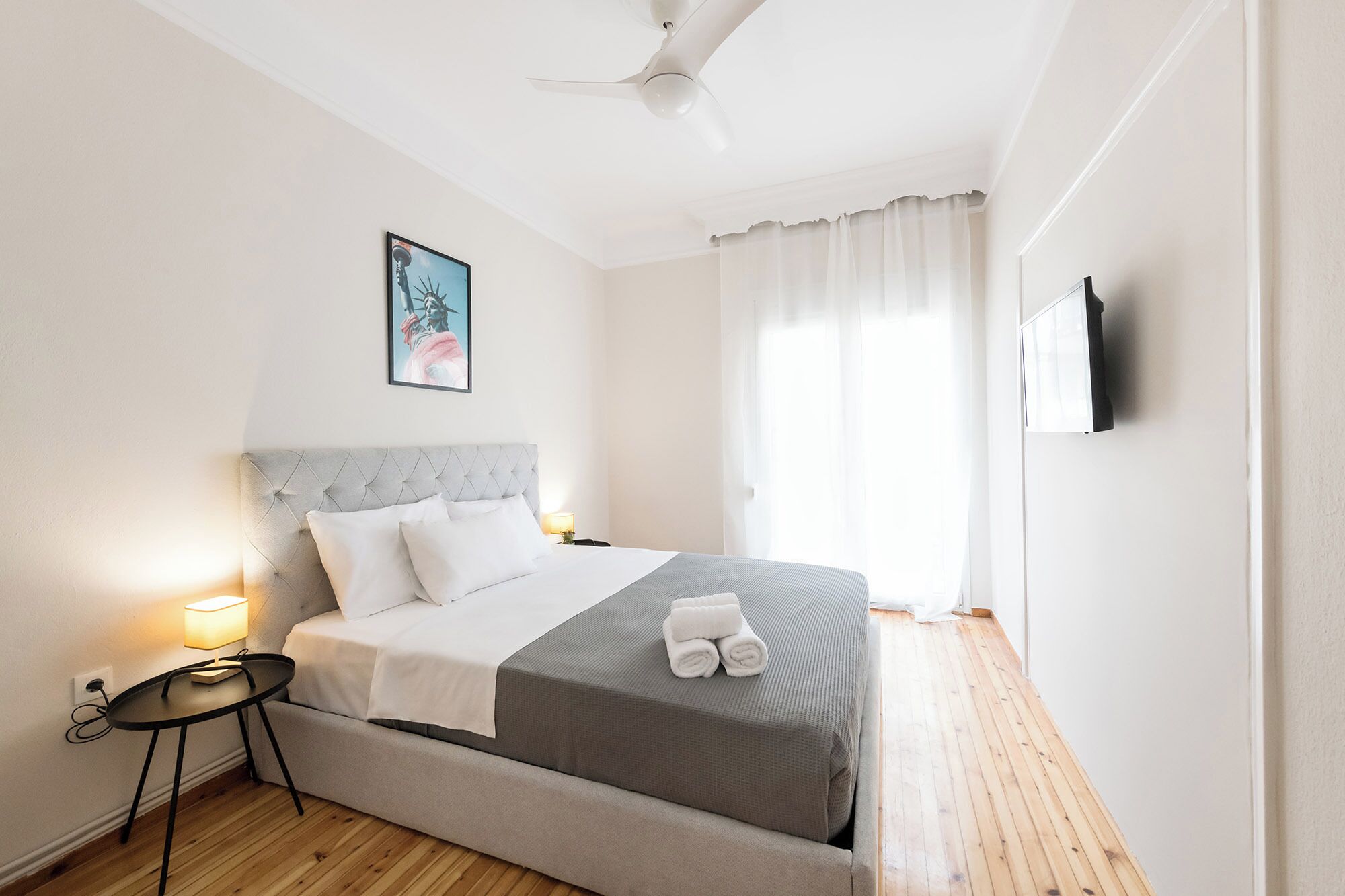 A neatly arranged bedroom with a bed, bedside table, lamp, and a painting on the wall.
