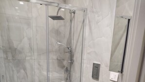 Ett modernt badrum med en dusch som är avskärmad med glasväggar, en toalett och ett handfat.