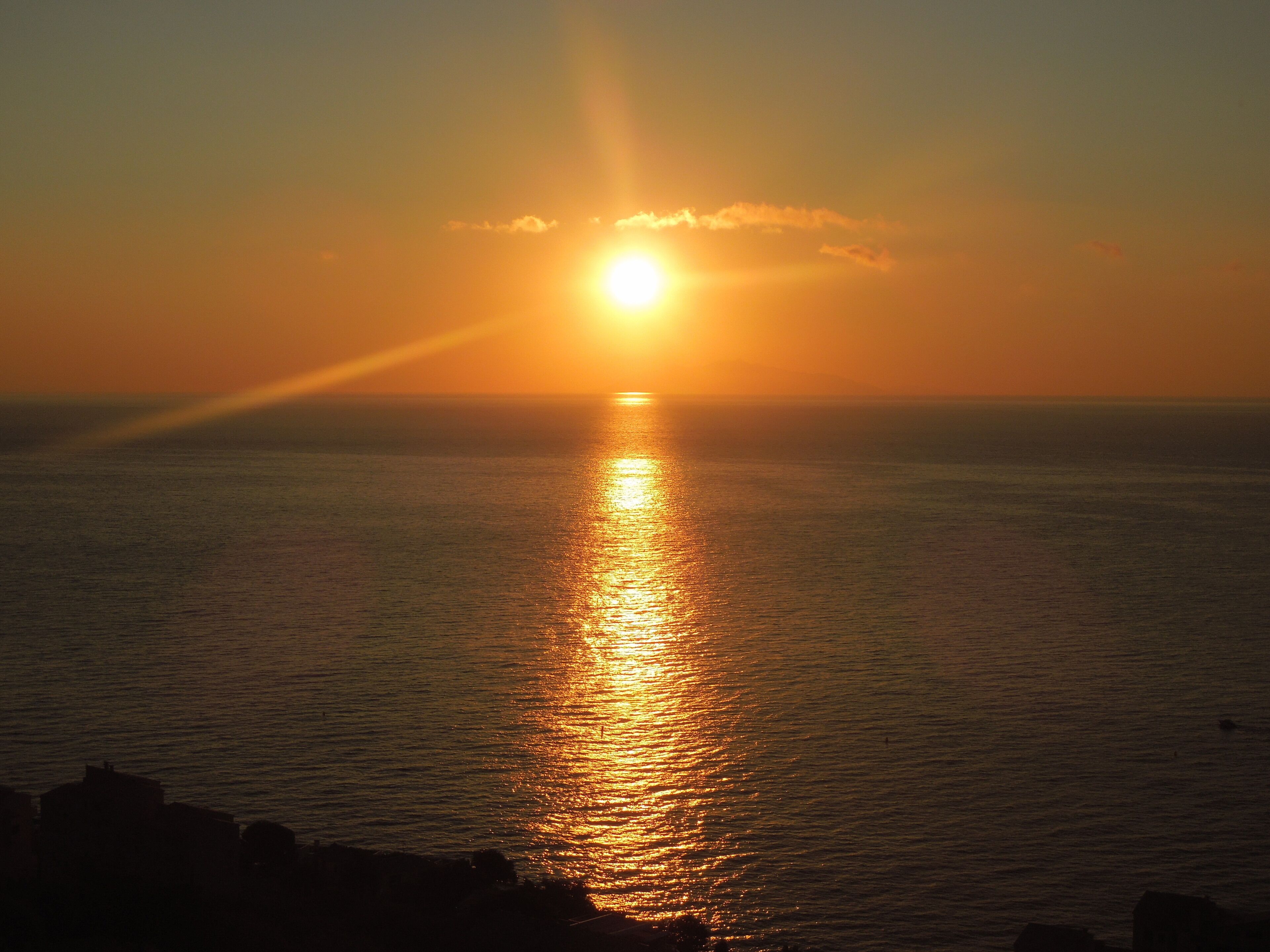 Un atardecer sobre un mar tranquilo con horizonte despejado.