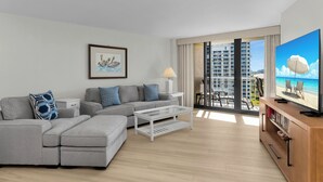 A modern living room with a grey sectional sofa, a white coffee table, and a television on a wooden stand. - South Seas Beachfront Haven (Marco Island)