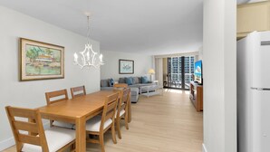 A modern living room with a dining area, a sofa, and a kitchen area. - South Seas Beachfront Haven (Marco Island)