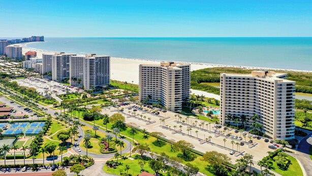 A high-rise hotel with a beach view, surrounded by greenery and a parking area. - South Seas Beachfront Haven (Marco Island)