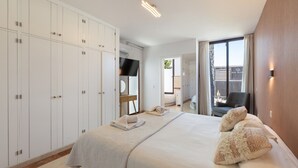 A hotel room with a large bed, a wardrobe, a TV, and a view of the outside. - Sea Breeze Jarea by Escape Home (Playa Blanca)