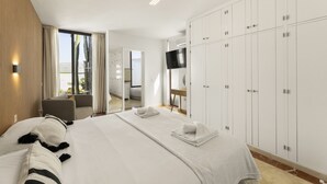 Ein Hotelzimmer mit einem großen Bett, einem Fernseher, einem Kleiderschrank und Blick ins Freie.