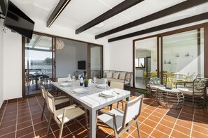 A dining area with a white table set for four, surrounded by wicker chairs.