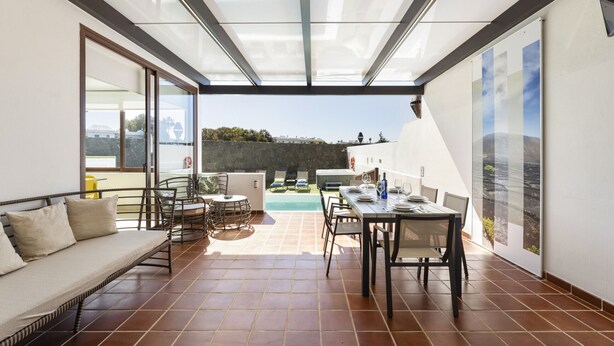Eine sonnige Terrasse mit Pool, Essbereich und einer Lounge mit einer Couch.
