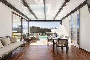 Une terrasse ensoleillée avec une piscine, un coin repas et un espace détente avec un canapé.