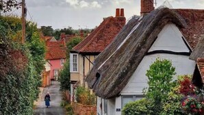 Una calle estrecha bordeada de casas tradicionales con tejados de paja.