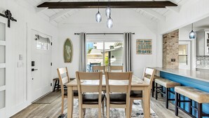 Un espace repas avec une table en bois, des chaises et des luminaires suspendus.