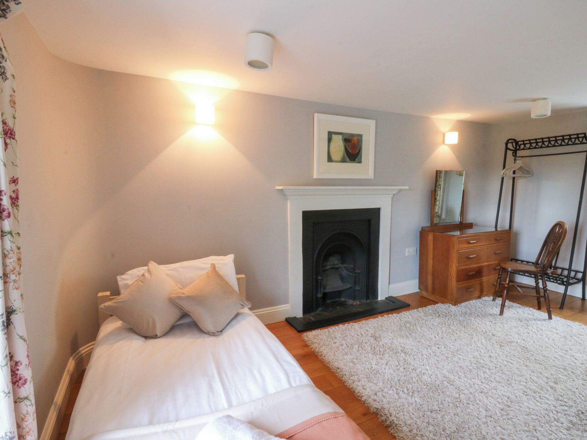 A bedroom with a bed, a fireplace, a dresser, and a chair.