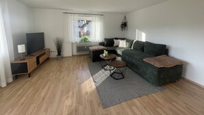 Un salon moderne avec un canapé, un téléviseur et un ventilateur de plafond.