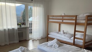 Une chambre d’hôtel avec un grand lit, un lit superposé et une vue sur les montagnes par la fenêtre.
