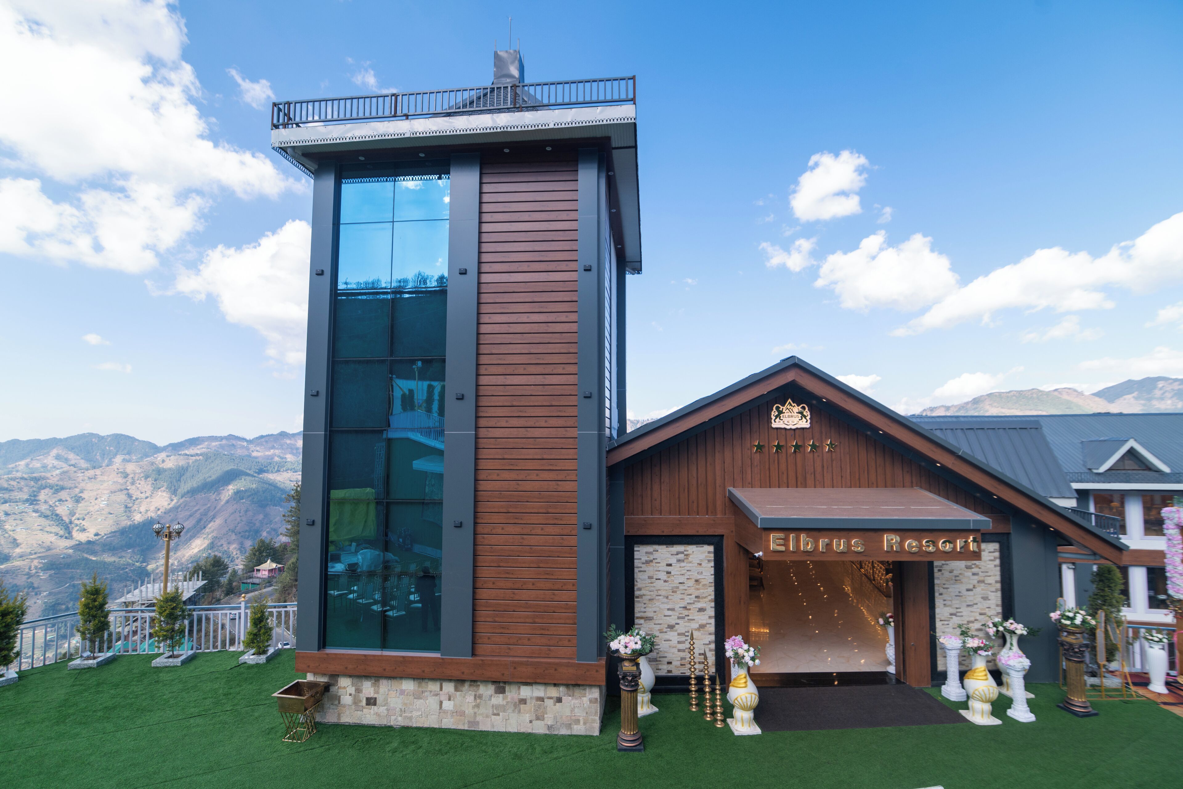 Un bâtiment moderne doté d’une tour de verre et d’une entrée en bois portant l’inscription « Eibrix Resort ».