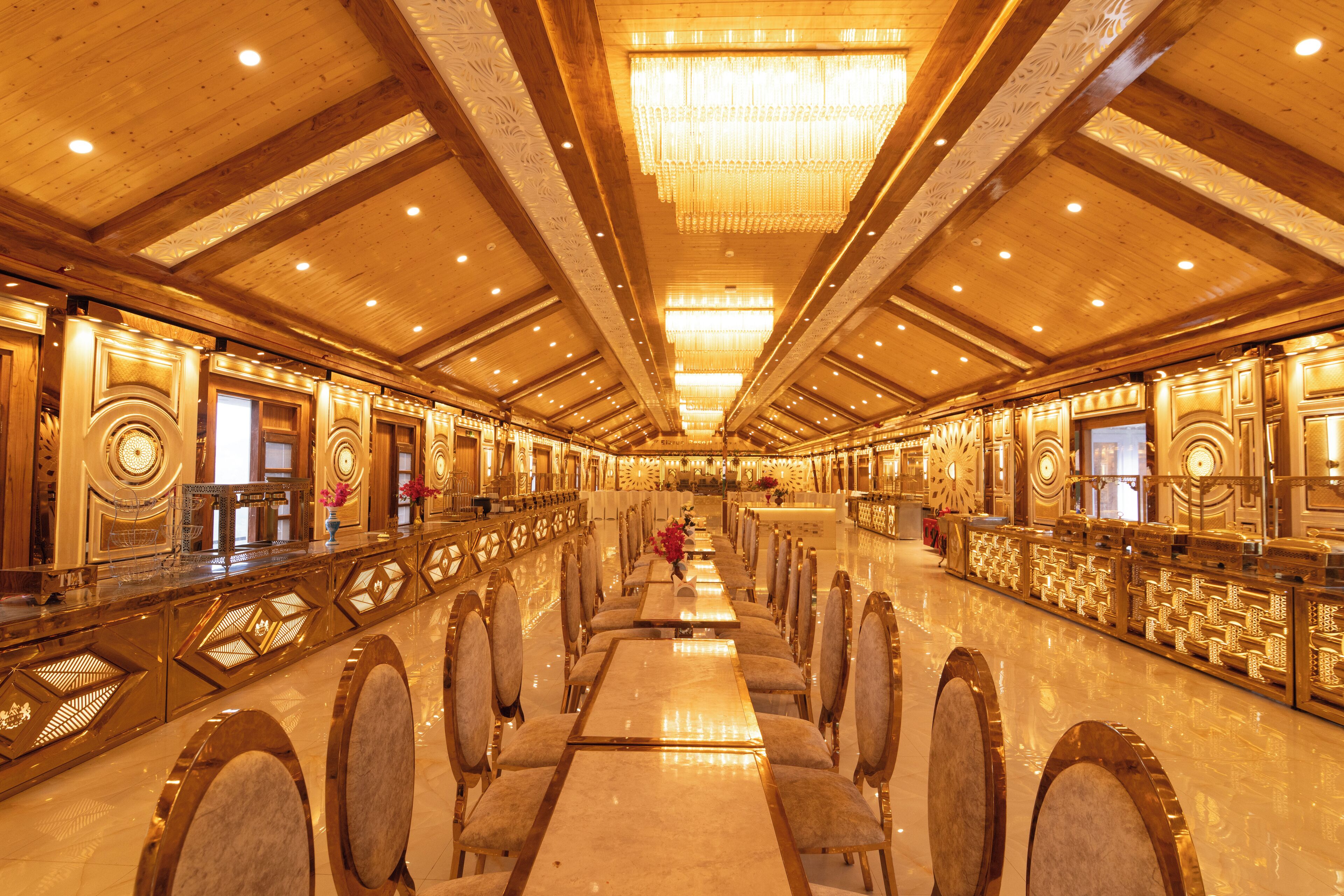 Un amplio salón de banquetes con largas mesas y sillas, decoraciones ornamentales en las paredes y un alto techo con candelabros.