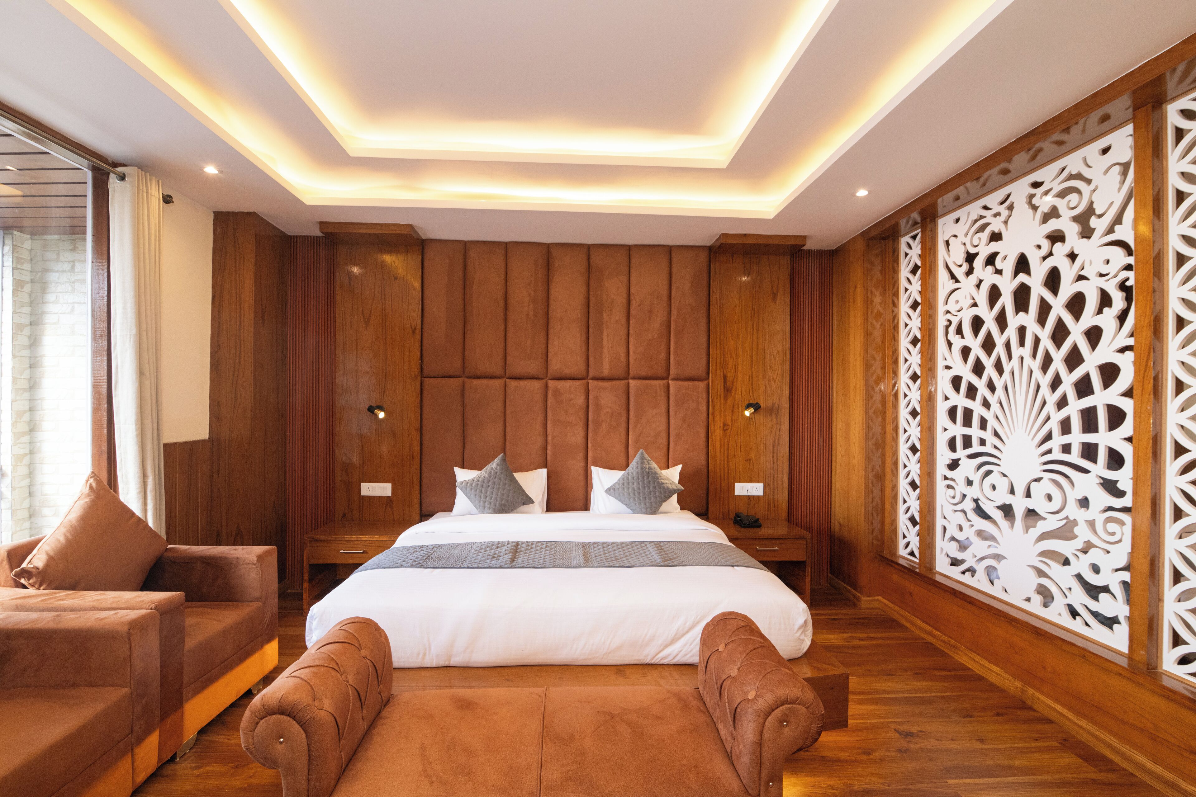 A modern bedroom with a large bed, wooden paneling, and a decorative white screen.