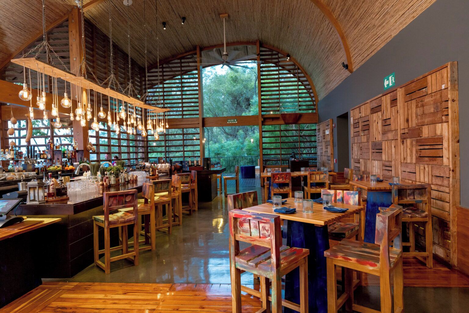 Un restaurant doté de meubles en bois, de luminaires suspendus et de grandes fenêtres.