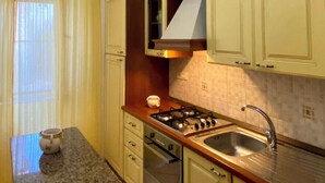 Cocina compacta con estufa a gas, lavamanos y microondas.