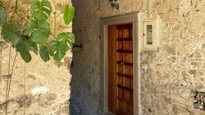 A narrow stone corridor with a wooden door, a small window, and a lantern above. - Il Granaio del Barone (Casal Velino)