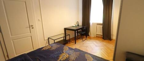 A bedroom with a bed, a desk, and a chair.