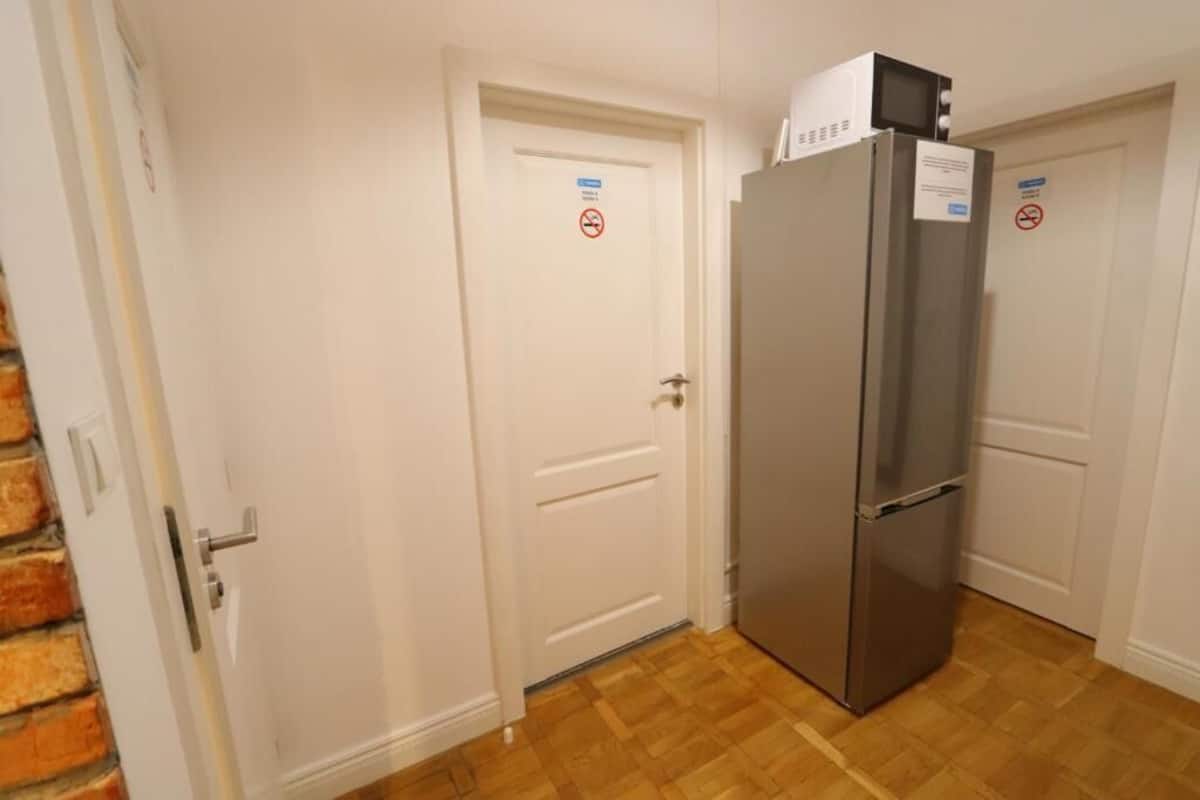 A kitchen with a stainless steel refrigerator, white doors, and a wooden floor.