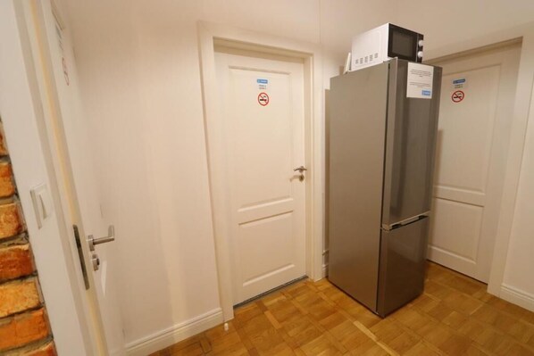 Una cocina con un refrigerador de acero inoxidable, puertas blancas y piso de madera.