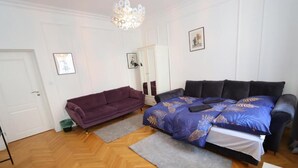 A bedroom with a bed, a purple sofa, a mirror, and a chandelier. - Fantastic Inn Warsaw - KP69 (Warsaw)