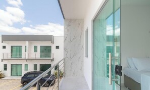 A modern building with a balcony, a car parked outside, and a bed inside. - Apt 3 Bedrooms in Condo w/ Pool Csv0006 (Porto Seguro)