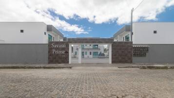 Entrada de un edificio con un cartel que dice 'Savassi Prime 151' y un camino de entrada porticado.