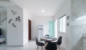 A modern kitchen with a dining area, white walls, and a refrigerator. - Apt 3 Bedrooms in Condo w/ Pool Csv0006 (Porto Seguro)