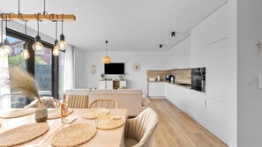 A modern kitchen with a dining area, wooden ceiling, and a TV mounted on the wall. - Boho Beach House by Villas Guide (Vodice)