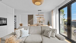 Een moderne woonkamer met een bank, eethoek en grote schuifpuien.