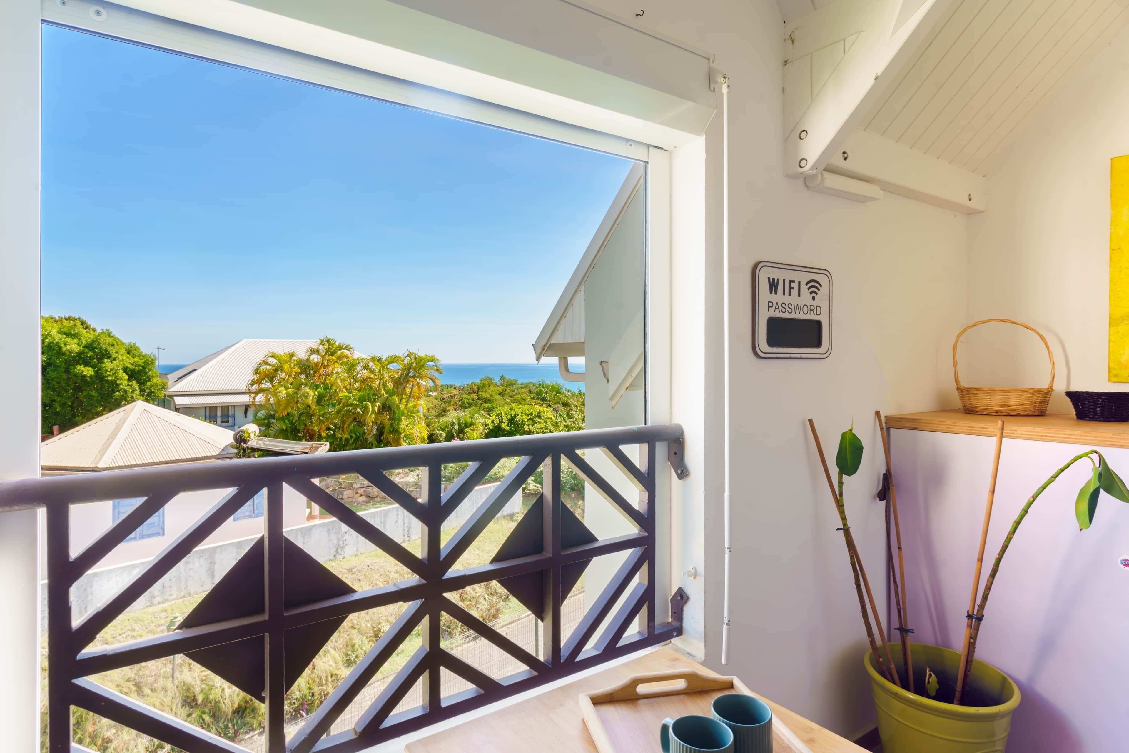 Ein Balkon mit Meerblick, ein Schild mit dem WLAN-Passwort, ein Korb und eine Pflanze.