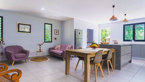 Eine moderne Küche mit Essbereich, ausgestattet mit einem Holztisch, Stühlen, einem violetten Sofa und einem Kühlschrank.