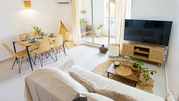 Ein modernes Wohnzimmer mit einer Couch, einem Esstisch, Stühlen, einem Fernseher und einem Balkon mit Blick.