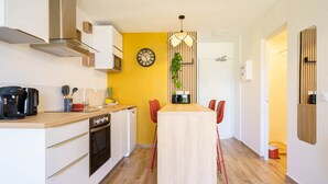 Una cocina moderna con una pared de acento amarilla, una mesa de comedor de madera, sillas rojas y un reloj.