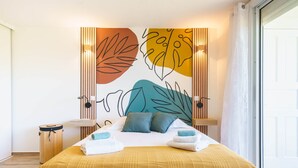 Habitación de hotel moderna con una cama grande, un mural decorativo y vistas al exterior.