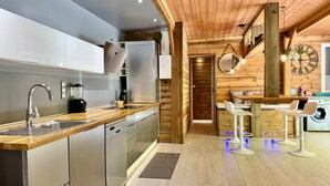 Una cucina moderna con elettrodomestici in acciaio inossidabile, elementi in legno e un'area pranzo con sgabelli da bar.