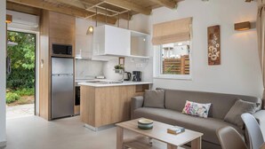 Een moderne keuken met een vastgezet kookeiland, een koelkast en een magnetron. Er is een houten plafond en een raam met uitzicht op groen.