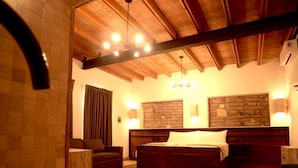 A spacious bedroom with a large bed, a wooden ceiling, stone walls, and a bathtub. - Hotel Villa de la Parra (Parras de la Fuente)
