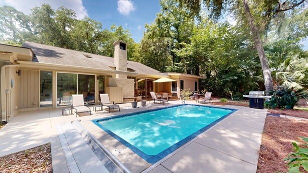 Una casa con piscina, mobili da esterno e una veranda coperta.