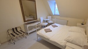 A bedroom with a bed, a chair, a small table, a mirror, and a window. - Schloss Burgscheidungen – Gästehaus (Laucha an der Unstrut)