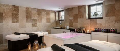 Un spa moderno con una bañera grande, dos camillas de masaje y un tocador con artículos de aseo.