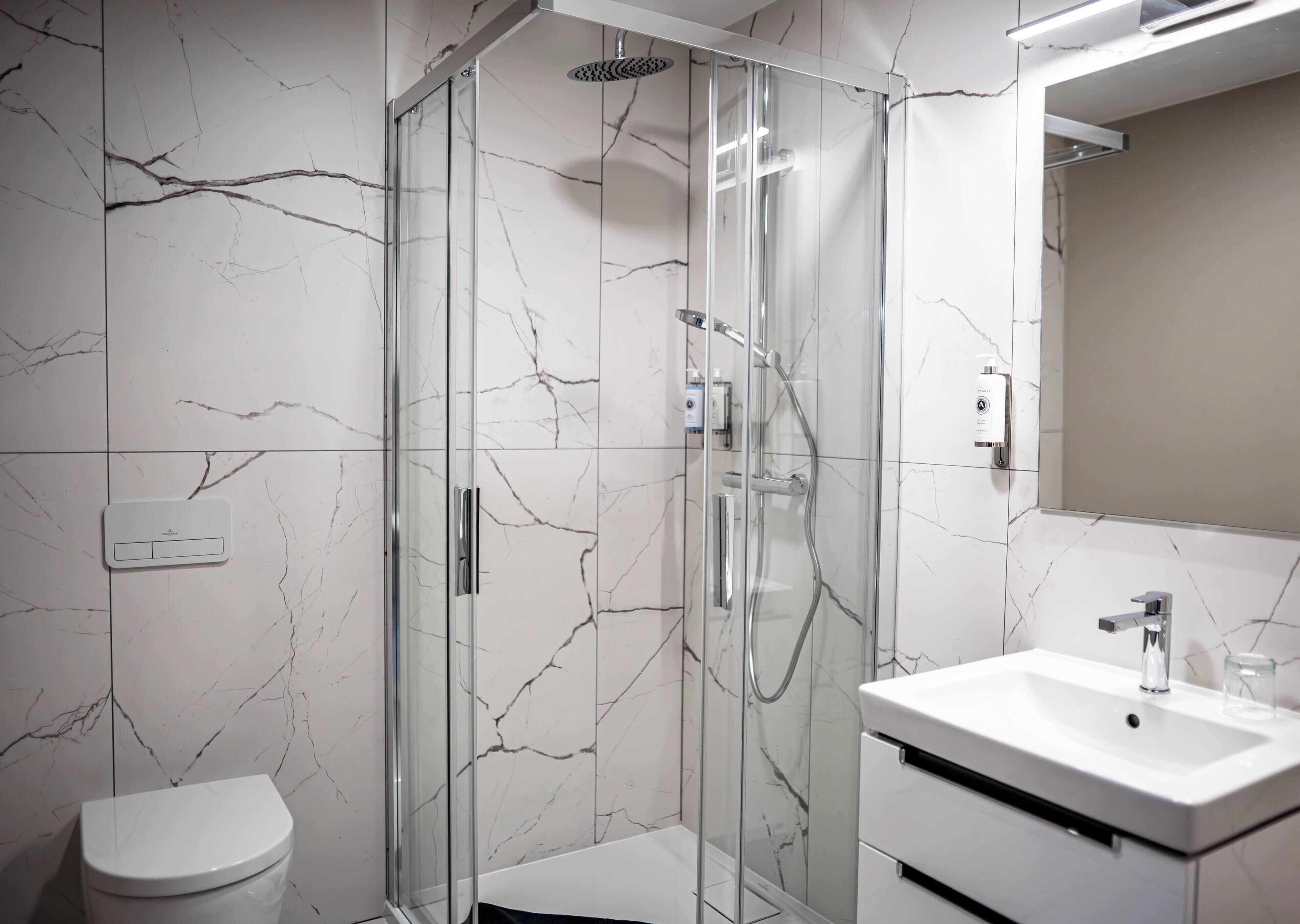 A modern bathroom with a glass-enclosed shower, a white sink, and a toilet.