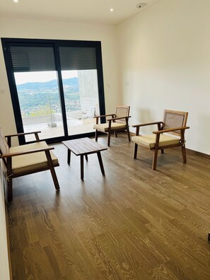 Habitació amb terra de fusta, una gran porta corredissa de vidre i dues cadires de fusta amb coixinets.