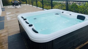 A hot tub on a wooden deck with a view of mountains.