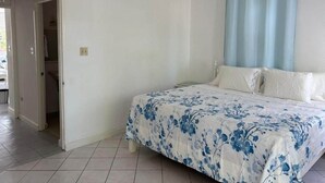 Ein Schlafzimmer mit Bett, Tür und einem Vorhangfenster.