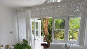 Ein Wohnzimmer mit einem weißen Sofa, einem Glastisch und einem blumengemusterten Bett.