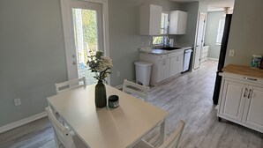 Eine moderne Küche mit weißen Schränken, einem Esstisch mit Stühlen und einem Deckenventilator.